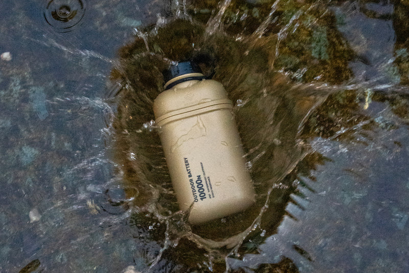 10000mAh rugged outdoor battery dropped into water with splashes, water-resistant power bank for outdoor use.