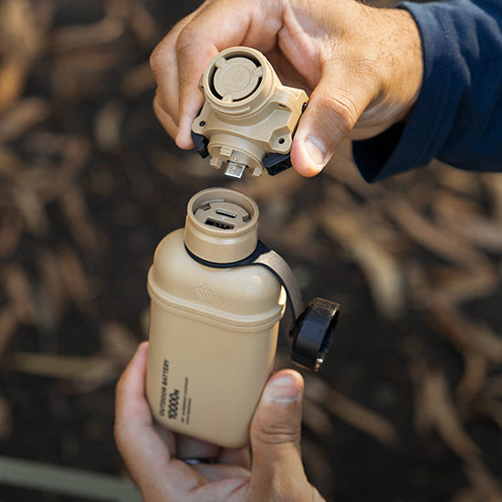 Person holding a beige power bank and attaching air pump attachment.