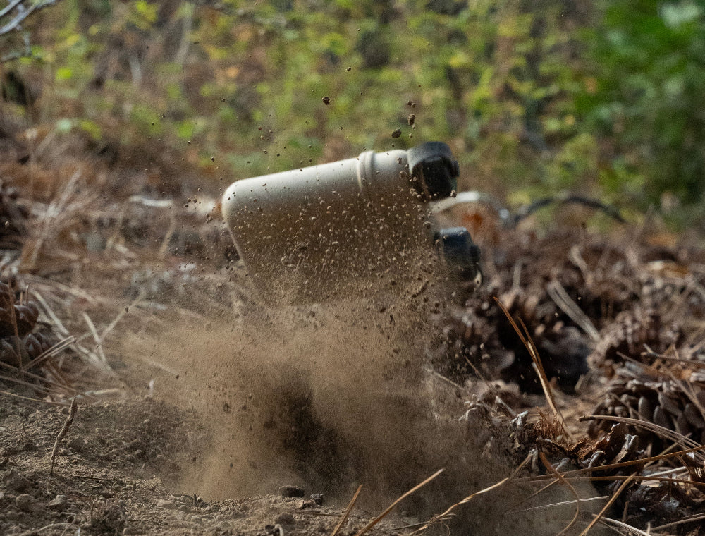 15000mah beige outdoor battery falls down on dirt with dust kicking up from the ground.