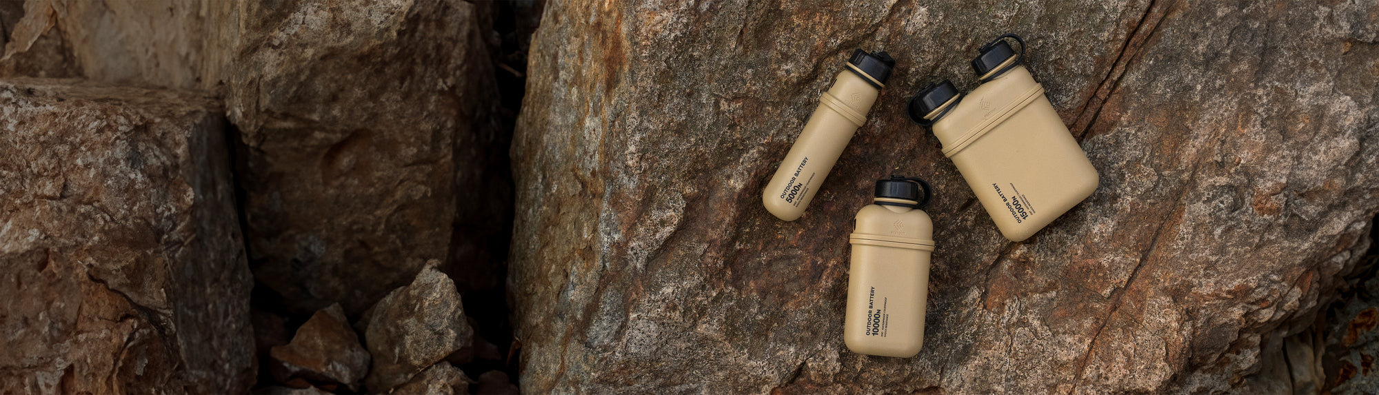 Three beige outdoor batteries lay on large rock.