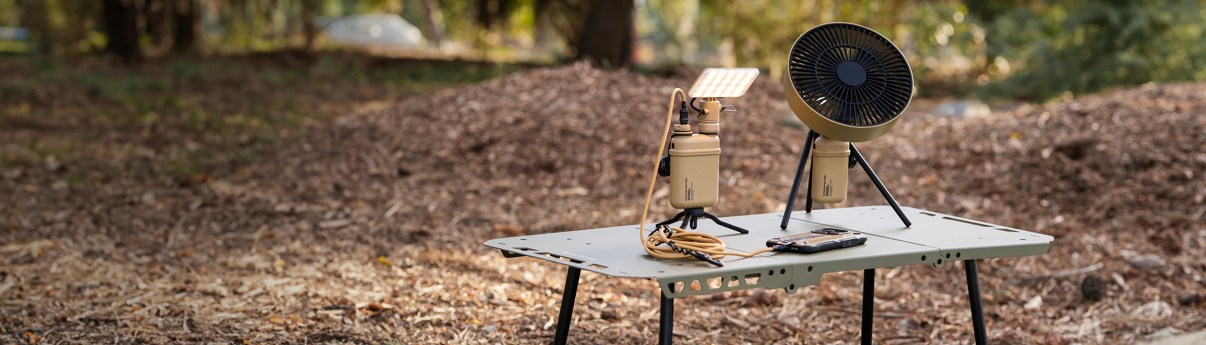 Outdoor setting with a small table with outdoor batteries, light, and fan on a table.