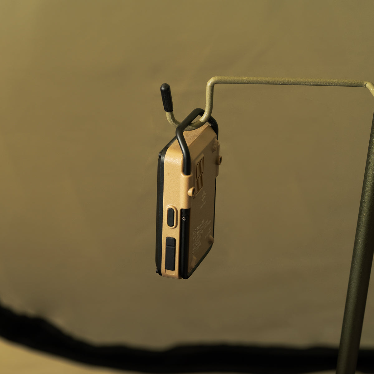 Beige co alarm being hung from a pole with a hook on the end