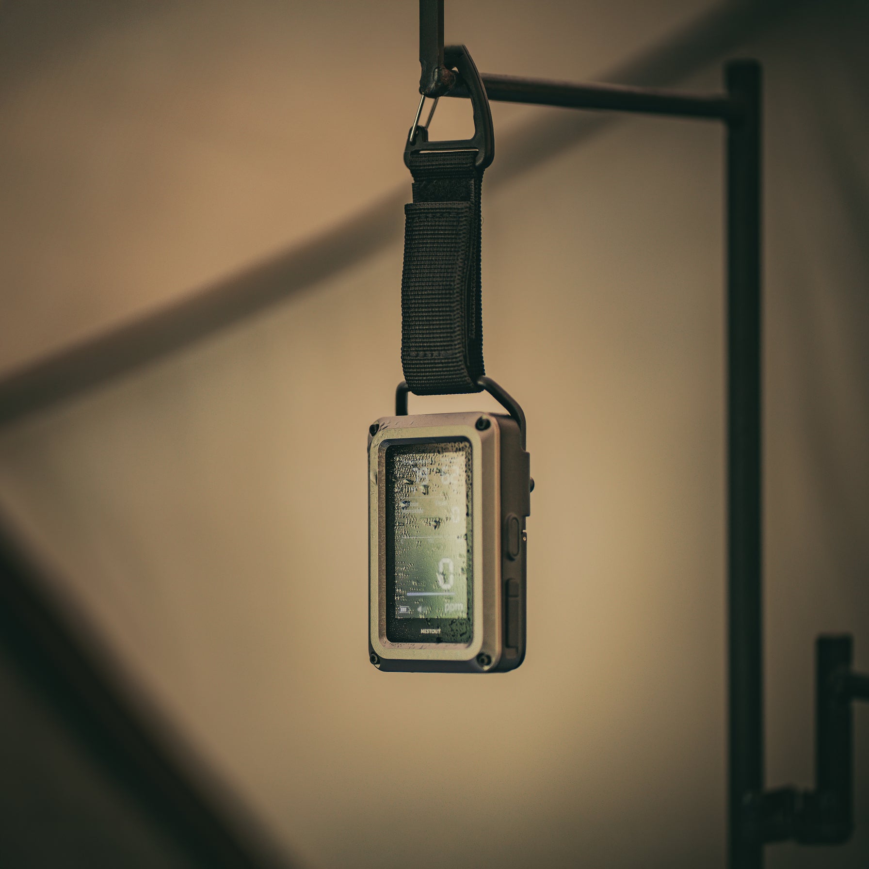 CO monitor on a strap hanging against a neutral background
