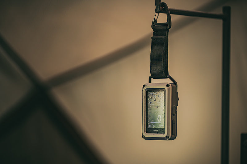 CO monitor on a strap hanging against a neutral background