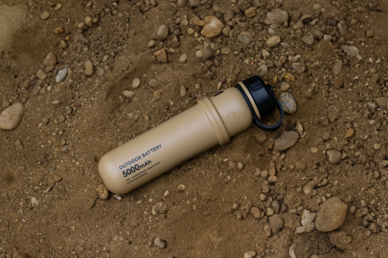 5000mAh rugged outdoor battery on dusty terrain,  compact dust-resistant power bank for camping and outdoor use.