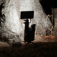 image of turned on nestout beige flash attached to 15k battery in the dark in front of a tree