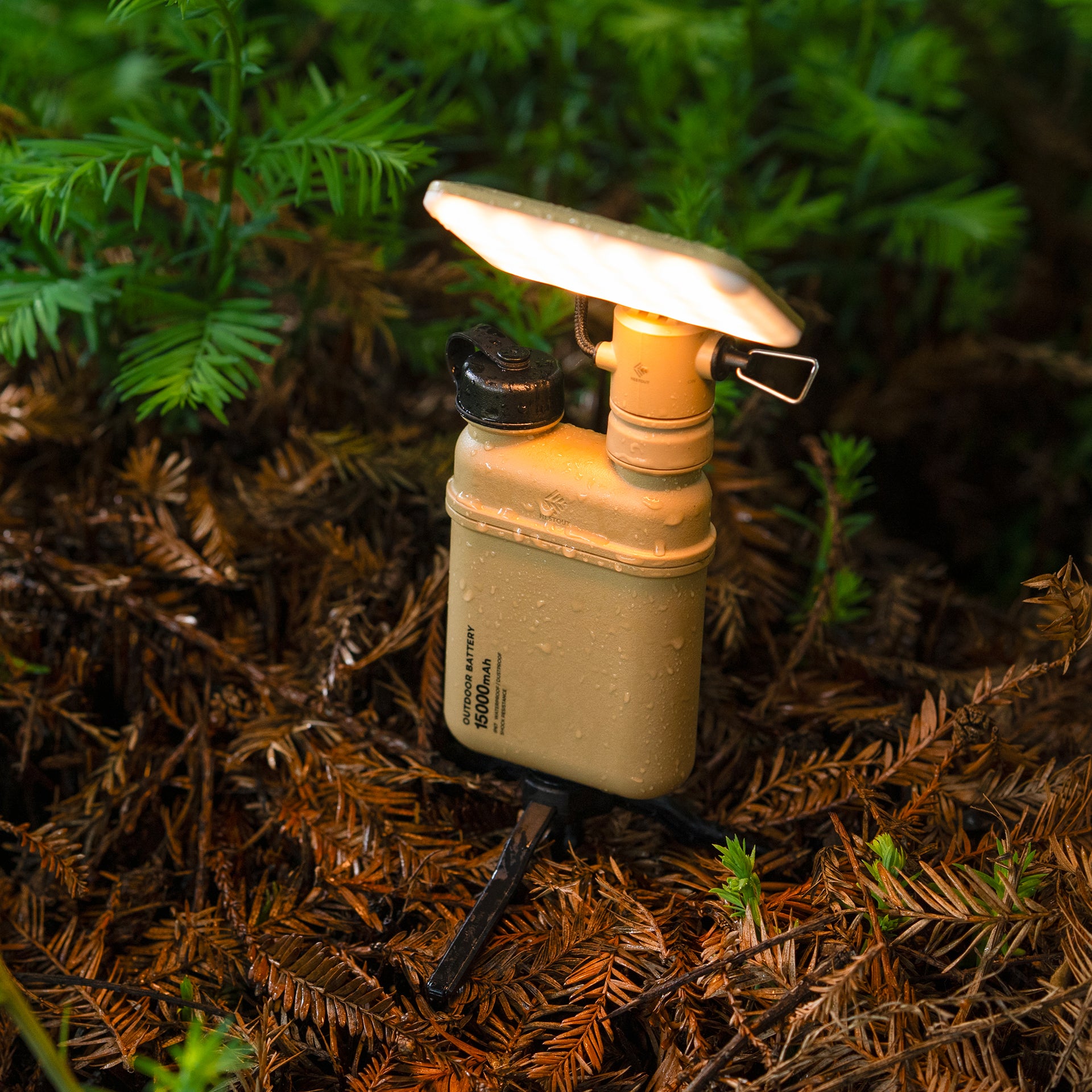 image of turned on wet nestout beige flash attached to 15k beige battery standing on tripod in the brush