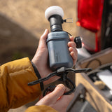Image of hand holding nestout black lamp with spacer attached 10k grey battery with opened tripod attached