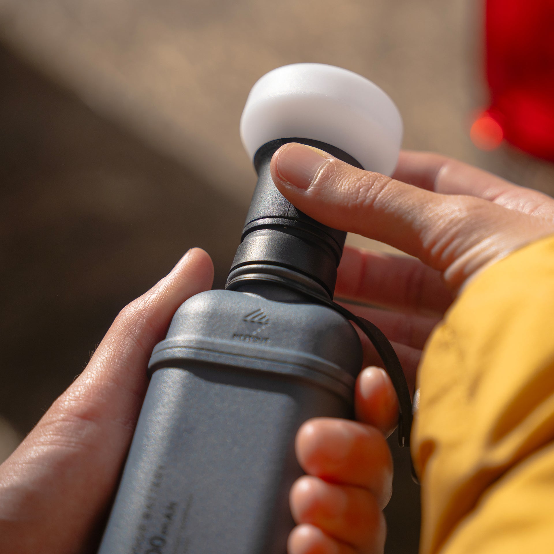 Image of hands turning on nestout black lamp with spacer attached connected to 10k grey battery