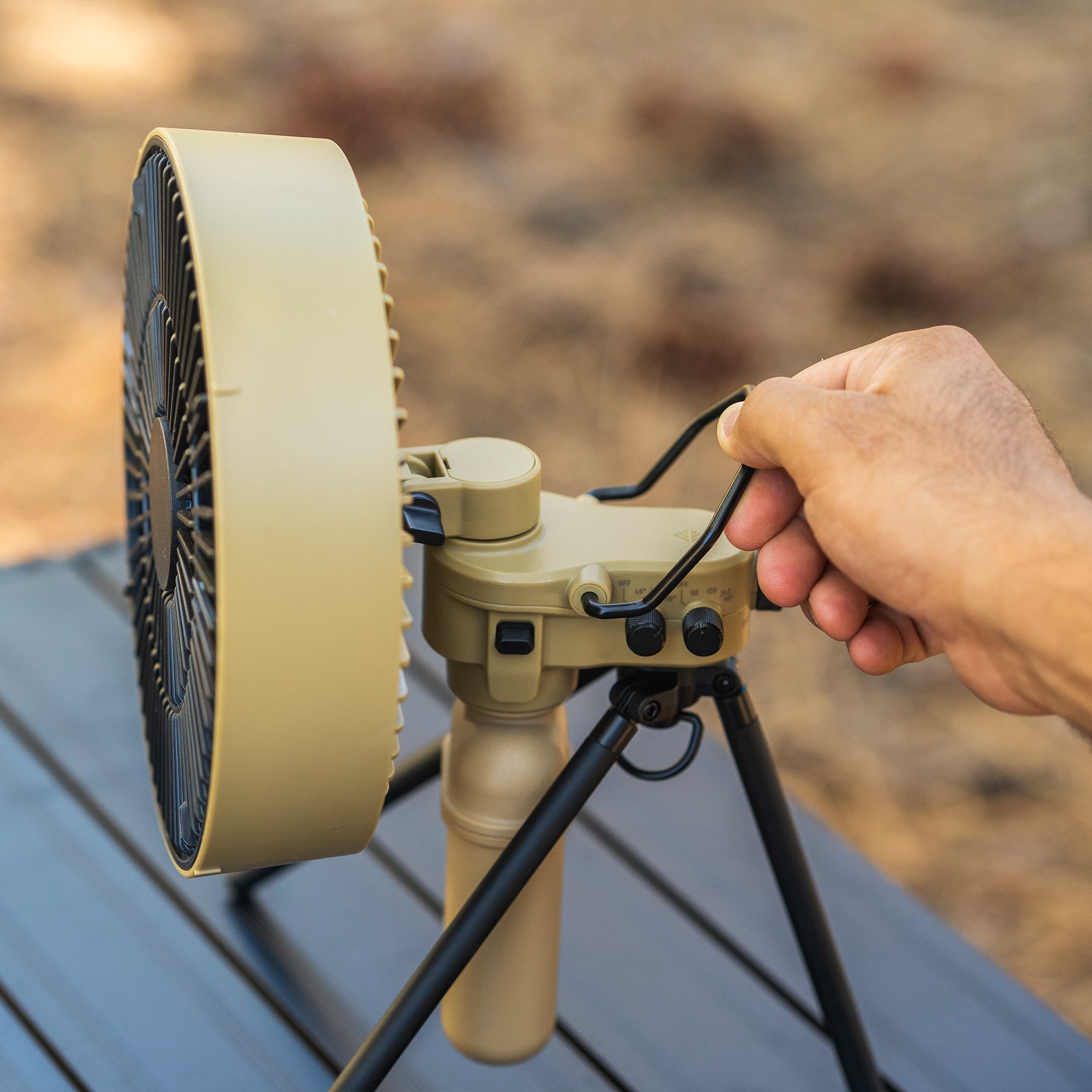 image of nestout beige fan with black metal hook being grabbed and 10k battery attached