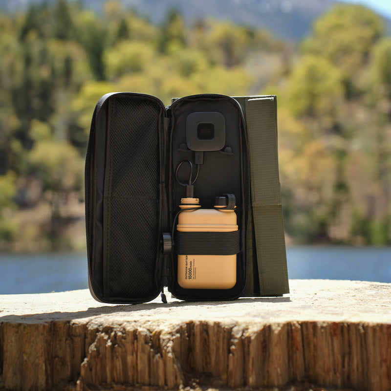 image of the nestout olive green 2 solar panel unfolded and the 15k beige battery connected to the USB connector resting on a tree stump at Jenks Lake
