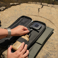 image of  hands connecting the nestout beige 10k battery into the nestout olive green 2 solar panel USB connector resting on a tree stump in Jens Lake
