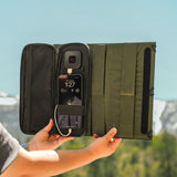 image of hands holding open the nestout olive green 2 solar panel with the USB connector connected to a smartphone