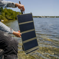 image of fisherman holding open towards the sun the nestout olive green 4 panel solar charger