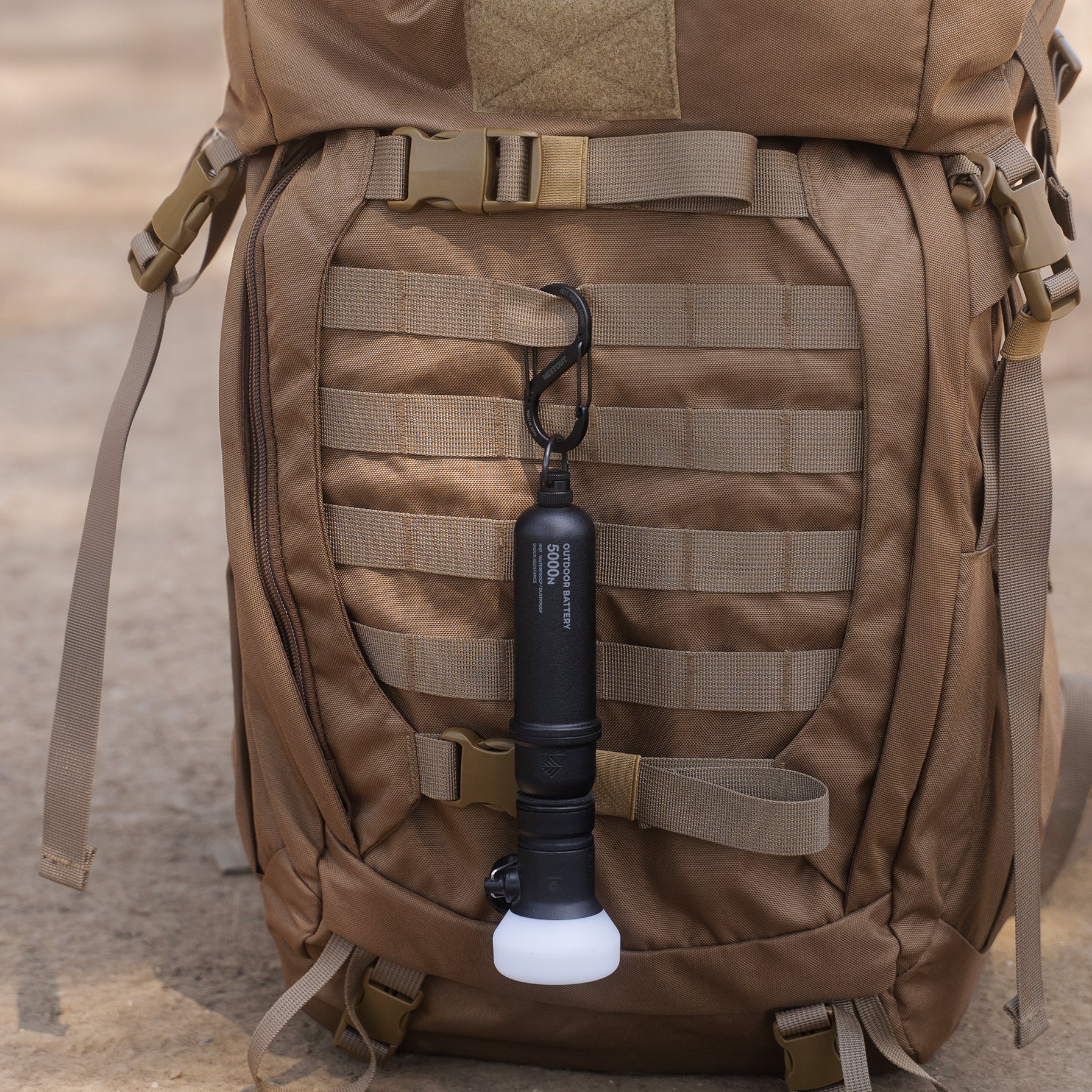 Black battery mount carabiner attached to a backpack and has a black 5k power bank attached to it along with a lamp attached
