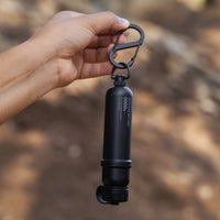 black battery mount carabiner attached to a 5k black power bank being held up by a hand outdoors
