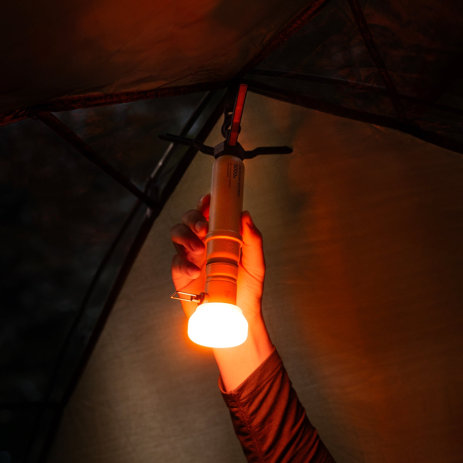 5k power bank hanging from tent with a lamp attachment that has an orange filter attached