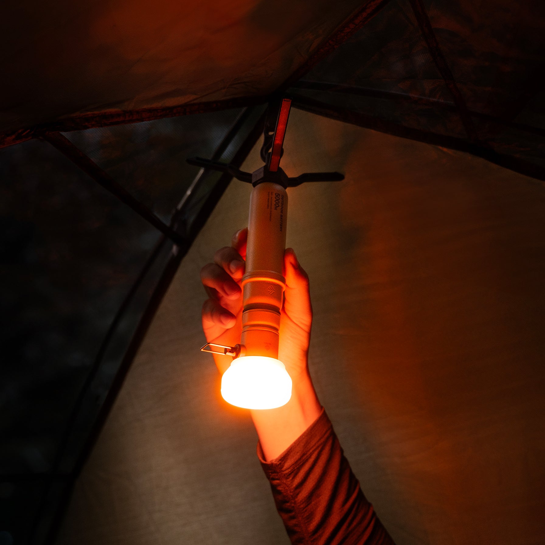 5k power bank hanging from tent with a lamp attachment that has an orange filter attached