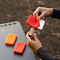 person holding a flash-1 light attachment and attaching a red light filter and two other filters on a table