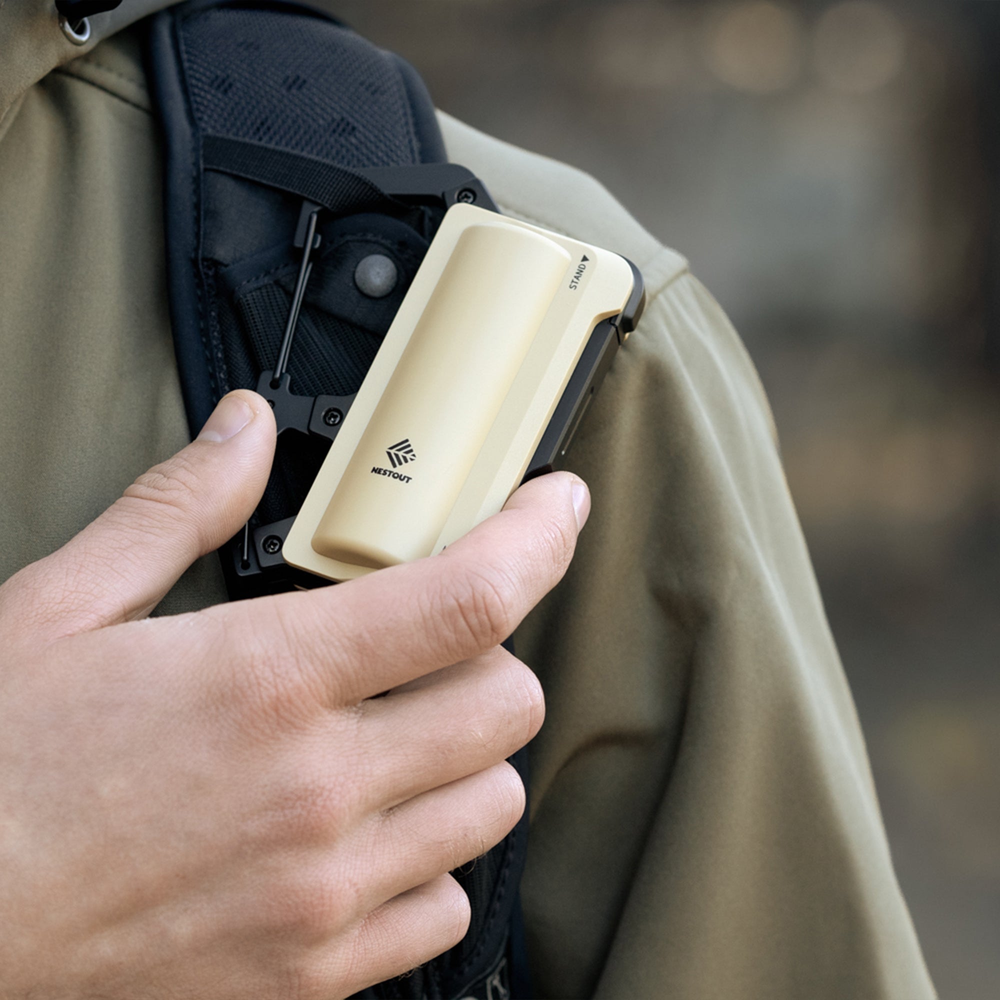 image of the nestout beige 5000n carabiner battery attached to backpack strap