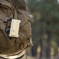 image of the nestout beige 5000n carabiner battery attached to a backpack