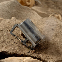 image of nestout black 5000n carabiner battery covered in dirt on rocks