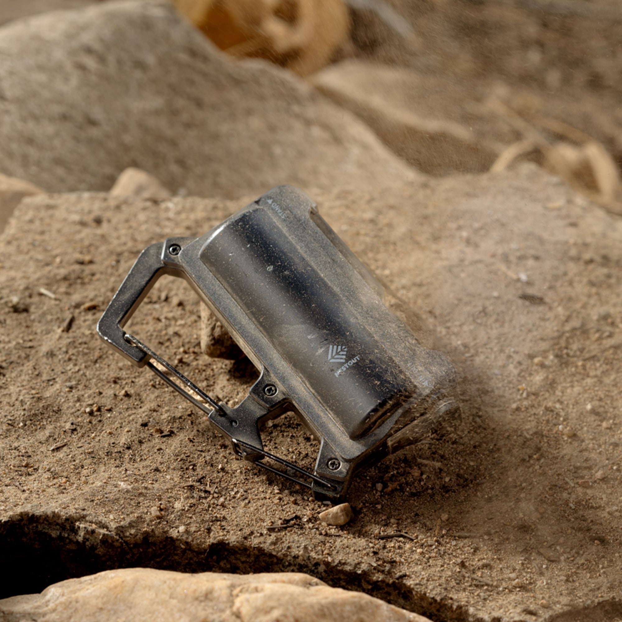 image of nestout black 5000n carabiner battery covered in dirt on rocks