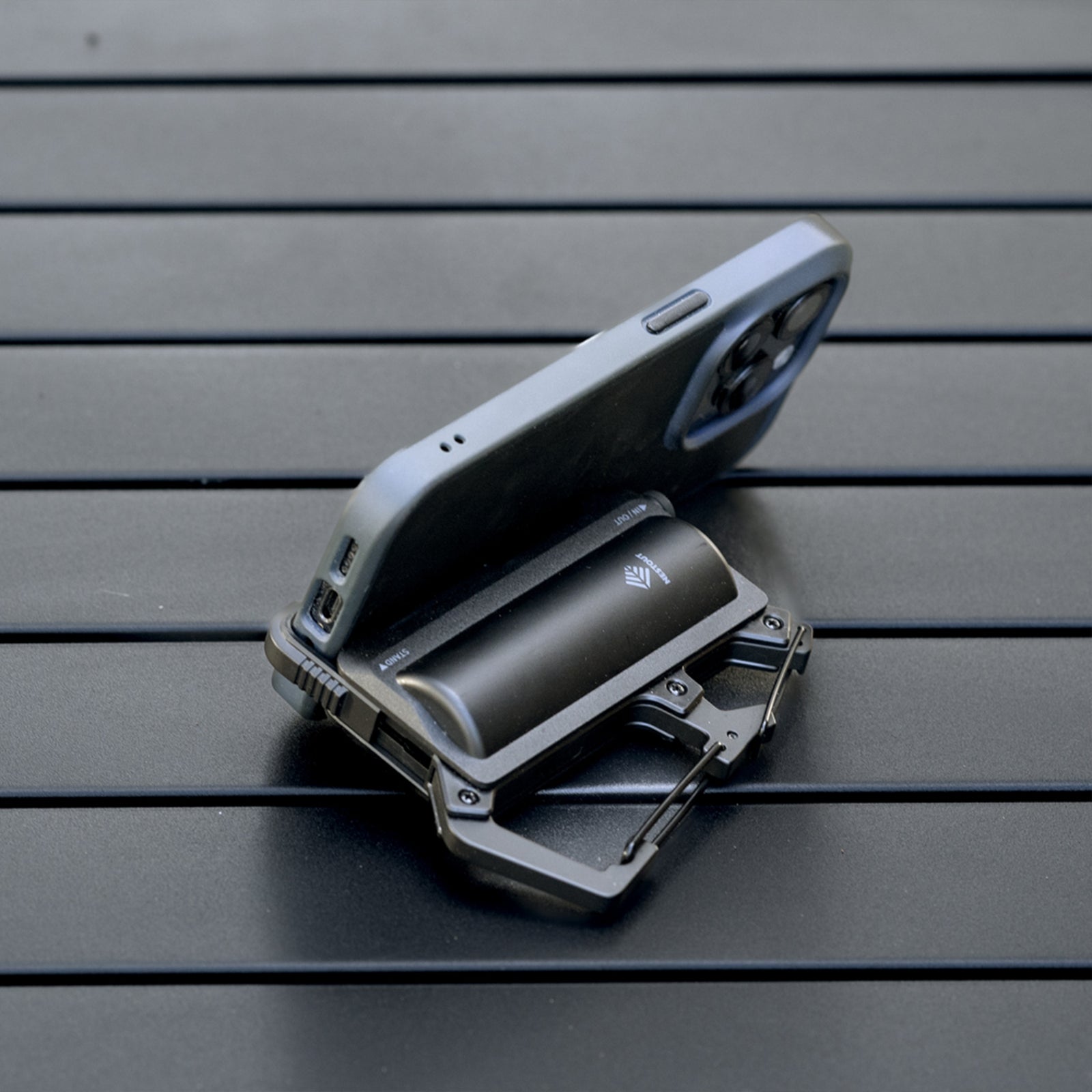 image of the nestout black 5000n carabiner battery being used as a phone stand on a table