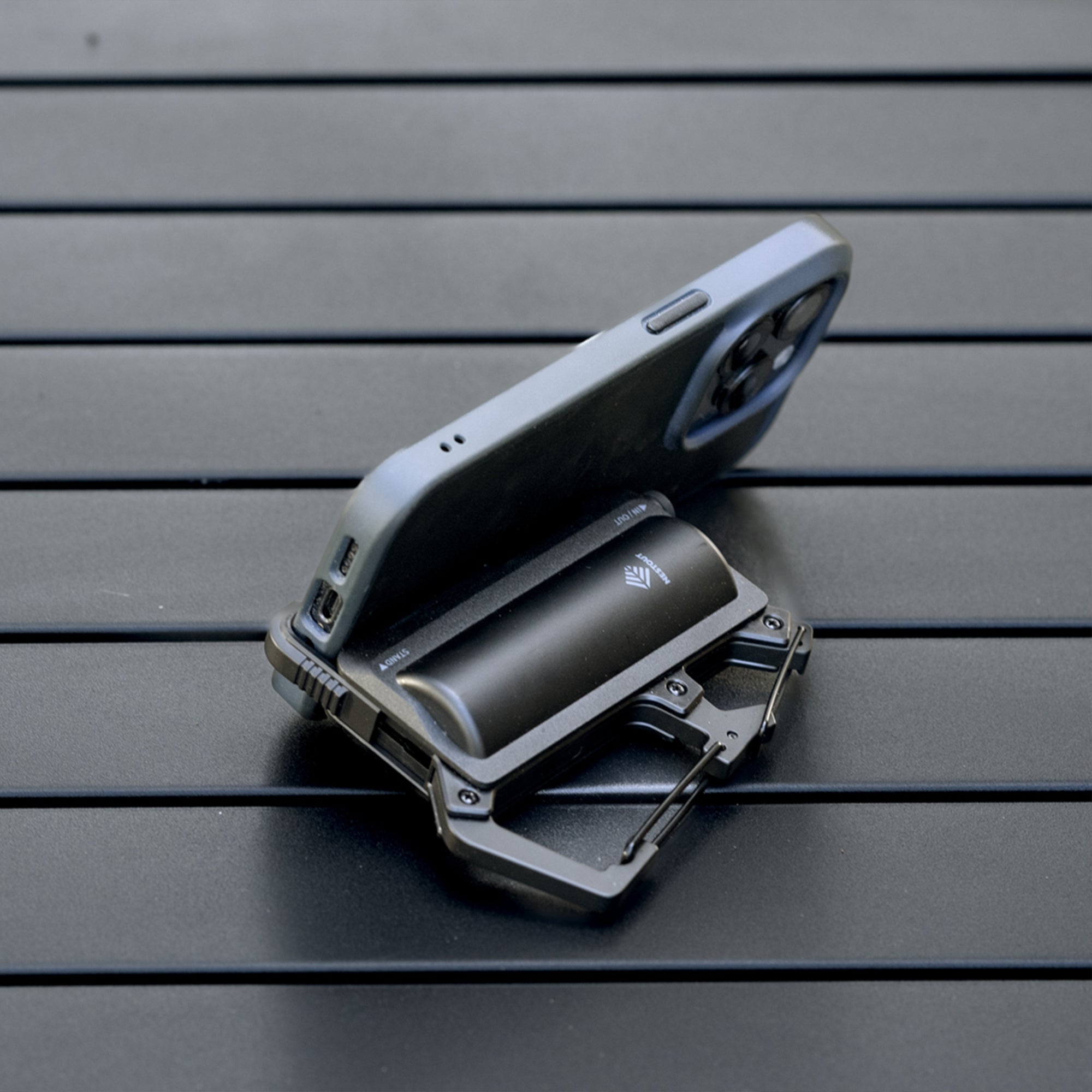 image of the nestout black 5000n carabiner battery being used as a phone stand on a table