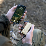 image of hiker sitting down using the nestout 5000n carabiner battery to charge smartphone