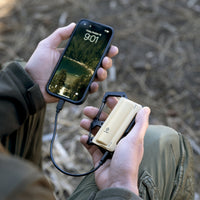 image of hiker sitting down using the nestout 5000n carabiner battery to charge smartphone