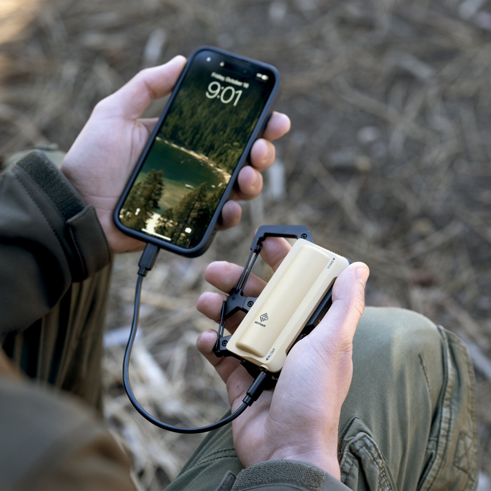 image of hiker sitting down using the nestout 5000n carabiner battery to charge smartphone