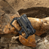 image of wet nestout black 5000n carabiner battery resting on rocks