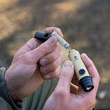 image of hiker hands placing the AAA battery into the nestout beige whistle light