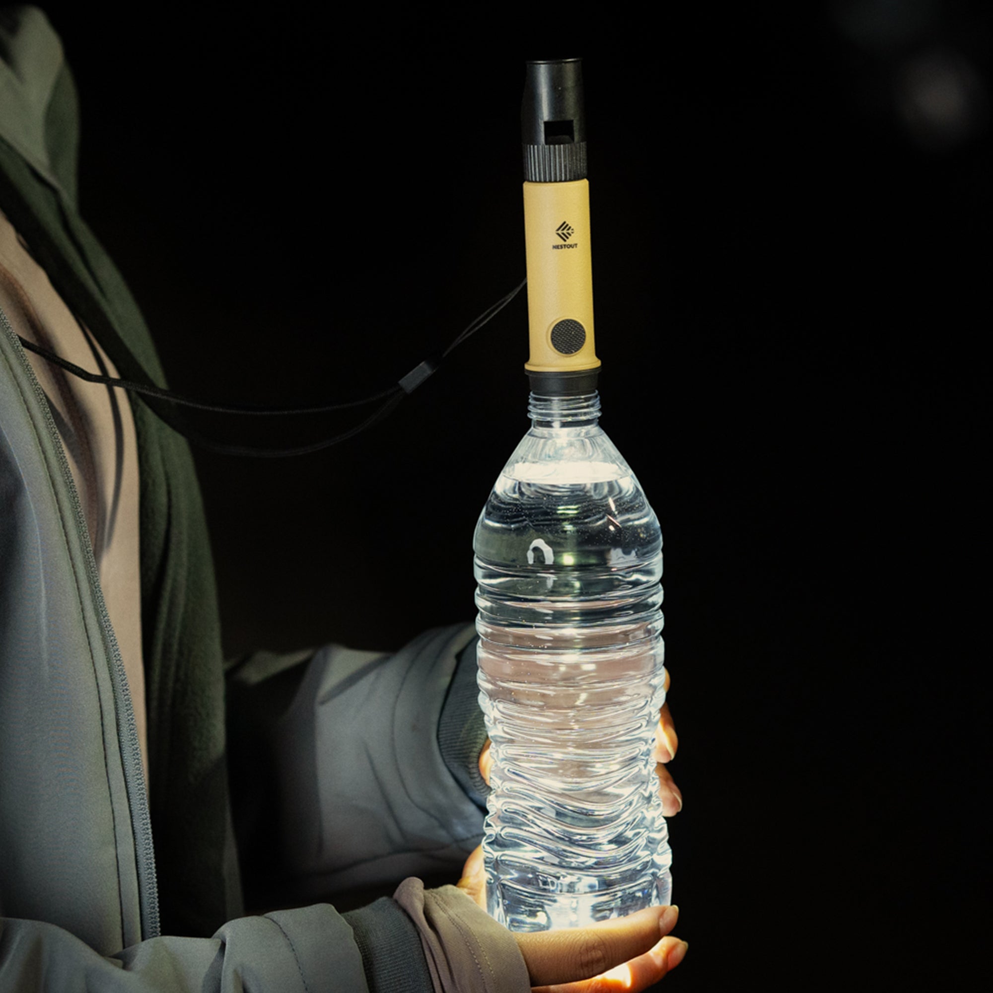 image of hiker in the dark holding a water bottle with the nestout beige light turned on and placed into the opening of the bottle in order to expand light