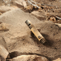 image of the nestout beige whistle light covered in dirt laying on rocks