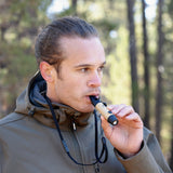 image of male hiker blowing on the nestout beige whistle which is hanging from his neck from the lanyard