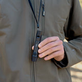 image of hiker holding the nestout black whistle light which is hanging from his neck from the lanyard 