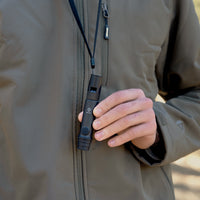 image of hiker holding the nestout black whistle light which is hanging from his neck from the lanyard 