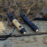 image of the nestout black and beige whistle lights turned on and resting on wood with hay on the ground