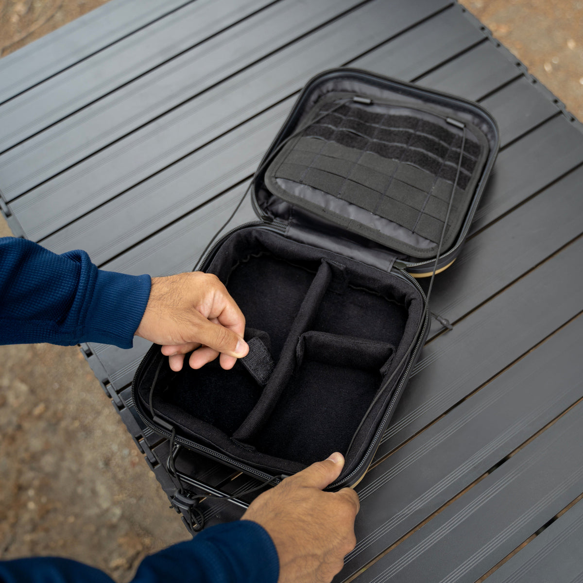 Person opening a black travel case on a gray surface