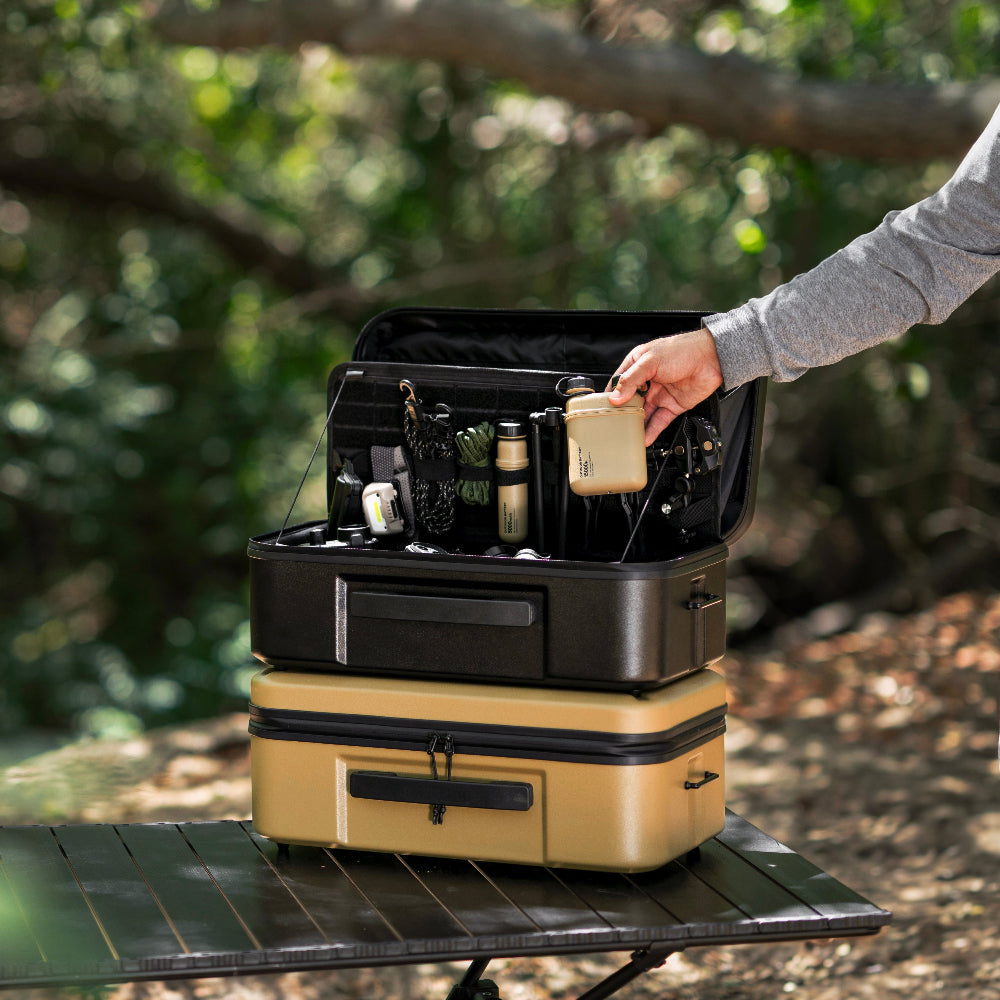 Stack of gear cases with a person opening one outdoors and pulling out NESTOUT battery