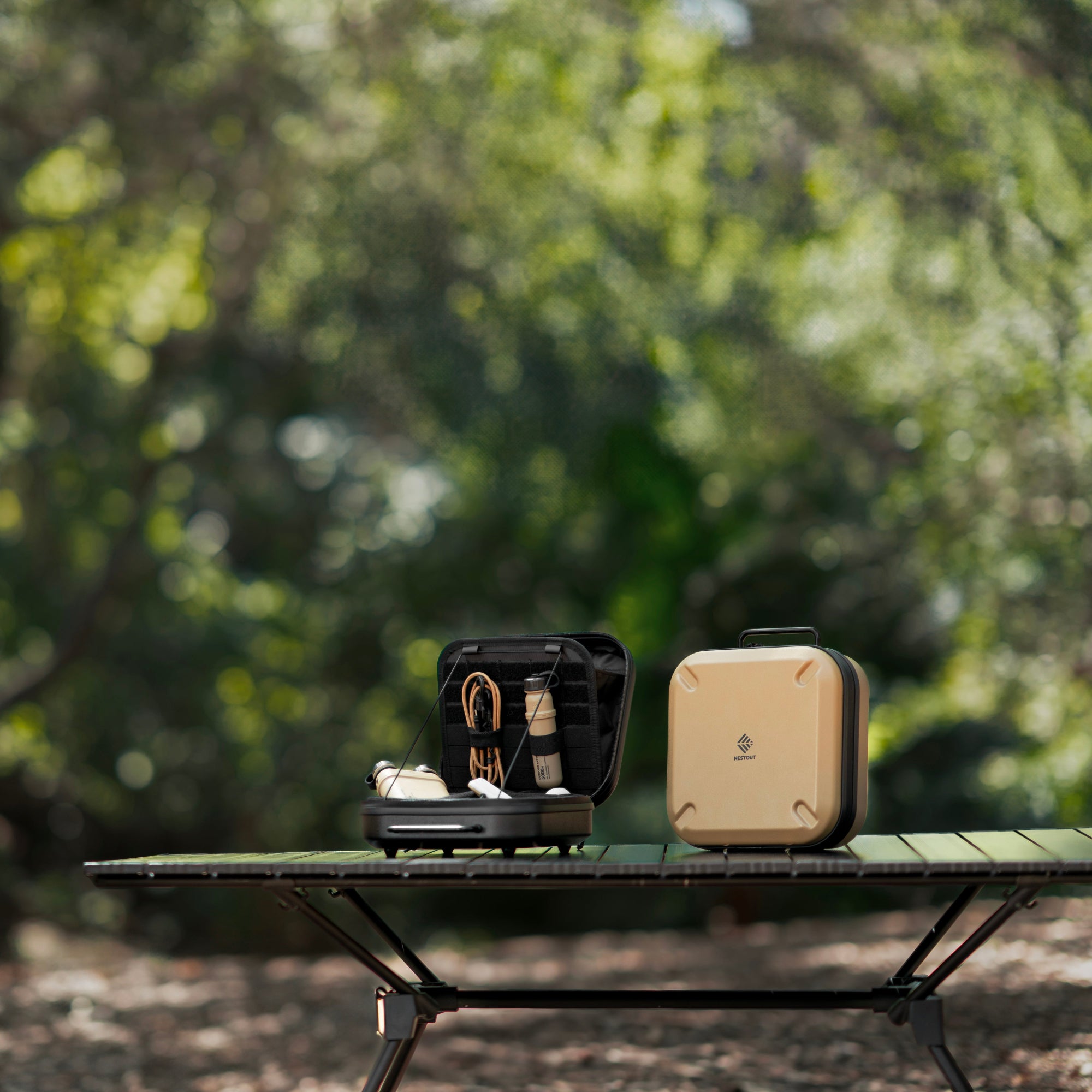 small black gear case opened next to beige gear case on black table in outdoor environment
