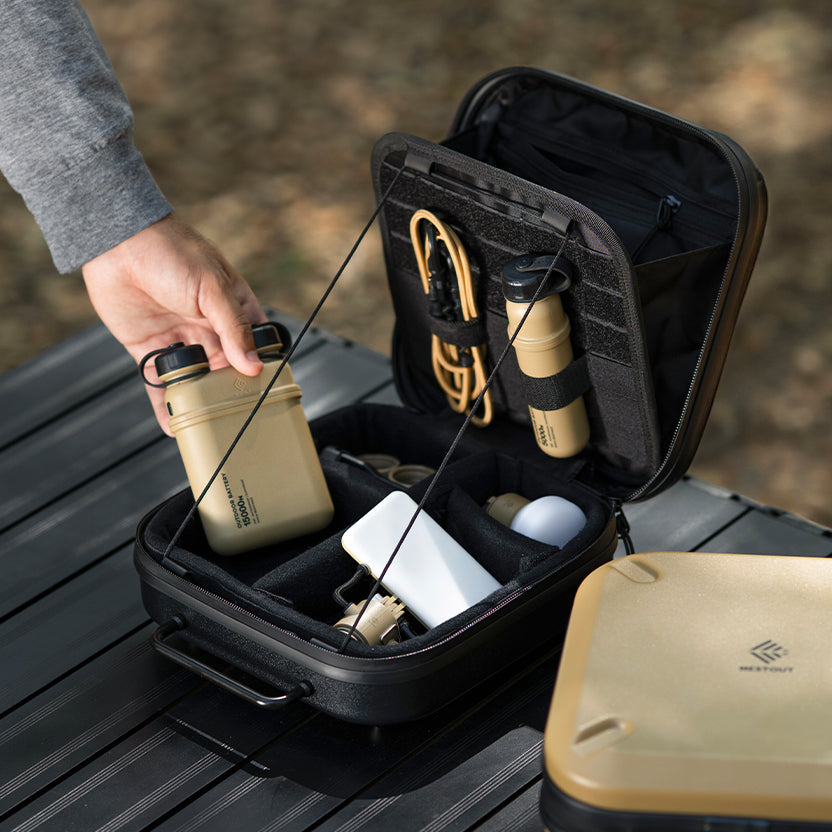 rugged black gear case open, with multiple power banks, charging cable, lamp and flash attachments and a beige gear case next to it. 