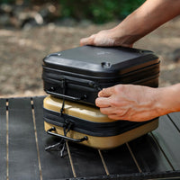 Two gear cases stacked on a table outdoors with a blurred background