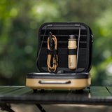 Small black and beige travel case with contents on a green surface outdoors
