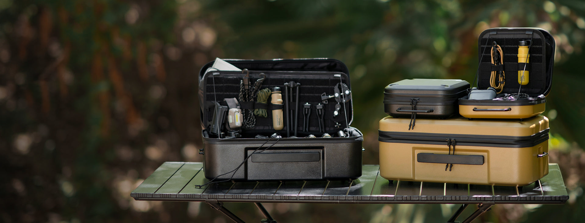 Two gear cases, one black and one beige with tools, on a green surface with a blurred natural background.