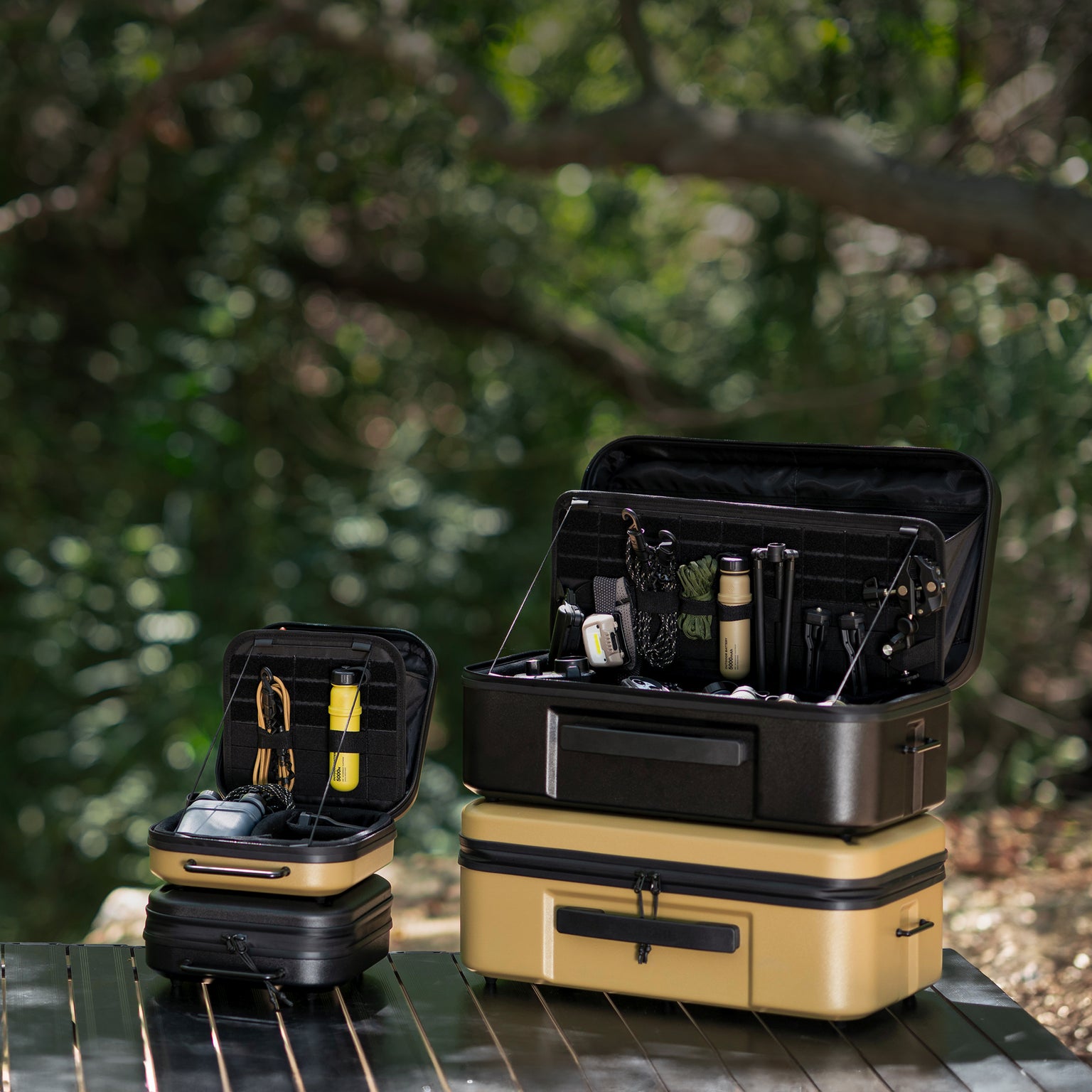 Set of black and beige gear cases with open compartments on a wooden surface with a blurred natural background.