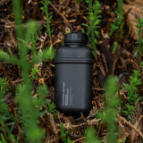 black 10000mAH power bank laying on some shrubs outdoors