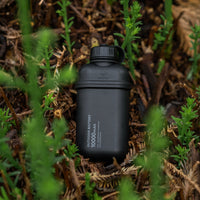 black 10000mAH power bank laying on some shrubs outdoors
